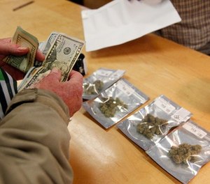 A customer purchases marijuana at Harborside marijuana dispensary, Monday, Jan. 1, 2018, in Oakland, Calif.