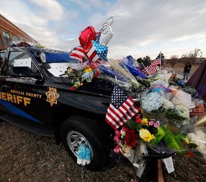 Tributes to a deputy killed in a shootout cover a patrol vehicle parked outside a Douglas County, Colo., Sheriffs Department substation Monday, Jan. 1, 2018, in Highlands Ranch, Colo.