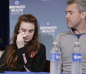 Marjory Stoneman Douglas High School shooting survivor Maddy Wilford, left, wipes a tear as her father David looks on during a press conference.