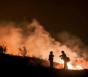In this Aug. 9, 2018, file photo, firefighters keep watch the Holy Fire burning in the Cleveland National Forest in Lake Elsinore, Calif.