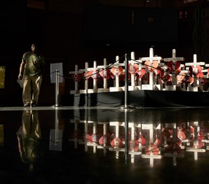 In this Friday, Sept. 21, 2018, photo, a man walks by crosses on display at the Clark County Government Center in Las Vegas. The crosses had been part of a makeshift memorial along the Las Vegas Strip erected in memory of the victims of the Oct. 1, 2017 mass shooting at a country music festival in Las Vegas. (AP Photo/John Locher)