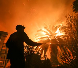 Park Billow, 27, sprays water on the hot spots in his backyard as the Woolsey Fire burns in Malibu, Calif., Friday, Nov. 9, 2018. Authorities announced Friday that a quarter of a million people are under evacuation orders as wind-whipped flames rage through scenic areas west of Los Angeles and burn toward the sea. (AP Photo/Ringo H.W. Chiu)