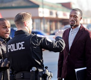 Byron Ragland, second right, talks with Kirkland police Sgt. Eric Karp near a frozen-yogurt shop that Ragland was kicked out of weeks earlier, Tuesday, Nov. 20, 2018, in Kirkland, Wash. The police department has apologized for an incident in which officers helped the owner of the Menchie's shop expel Ragland from the business because employees said they felt uncomfortable. (AP Photo/Elaine Thompson)