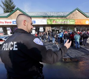 A Kirkland police officer directs traffic past a shop where Byron Ragland and local civil rights leaders addressed media members Tuesday, Nov. 20, 2018, in Kirkland, Wash. The police department there has apologized for an incident in which officers helped the owner of the Menchie's shop expel Ragland, an African-American man, from the business because employees said they felt uncomfortable. (AP Photo/Elaine Thompson)