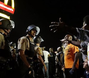 Officers and protesters face off along West Florissant Avenue, Monday, Aug. 10, 2015, in Ferguson, Mo.