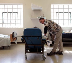 In this Sept. 12, 2012, file photo, Dr. David Mathis, visits with an inmate in the hospital unit at the California Medical Facility in Vacaville, Calif.