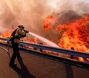 In this Nov. 12, 2018 file photo a firefighter battles a fire along the Ronald Reagan Freeway, aka state Highway 118, in Simi Valley, Calif.