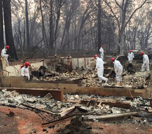 In this Nov. 15, 2018 file photo, volunteer rescue workers search for human remains in the rubble of homes burned in the Camp Fire in Paradise, Calif. A northern California sheriff's office has released the names of two more people who died in a devastating wildfire that killed at least 86 people. The Butte County Sheriff's office identified on Thursday, Jan. 31, 2019, the deceased as 74-year-old Robert Quinn of Paradise and 93-year-old Berniece Schmidt of Magalia.