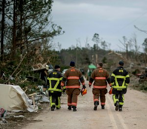 First responders walk through a neighborhood heavily damaged by a tornado a day earlier in Beauregard, Ala., Monday, March 4, 2019.