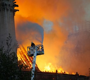 A fire fighter uses a hose as Notre Dame cathedral is burning in Paris, Monday, April 15, 2019. (AP Photo/Francois Mori)