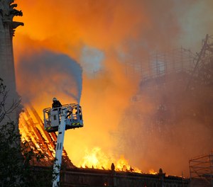 A fire fighter uses a hose as Notre Dame cathedral is burning in Paris, Monday, April 15, 2019. A catastrophic fire engulfed the upper reaches of Paris' soaring Notre Dame Cathedral as it was undergoing renovations Monday, threatening one of the greatest architectural treasures of the Western world as tourists and Parisians looked on aghast from the streets below.