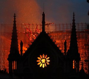 Flames and smoke rise from Notre Dame cathedral as it burns in Paris, Monday, April 15, 2019. Massive plumes of yellow brown smoke is filling the air above Notre Dame Cathedral and ash is falling on tourists and others around the island that marks the center of Paris.