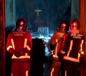 In this image taken from France Televisions video, firefighters stand at an entrance and look at the fire damage inside the Notre Dame cathedral in Paris, Monday April 15, 2019. Firefighters declared success Tuesday morning in an over 12-hour battle to extinguish an inferno engulfing Paris' iconic Notre Dame cathedral that claimed its spire and roof, but spared its bell towers.