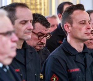 Paris fire brigade chaplain priest Jean-Marc Fournier, center bowing, listens to French President Emmanuel Macron addressing Paris Firefighters' brigade and security forces who took part at the fire extinguishing operations of the Notre Dame of Paris Cathedral fire, at the Elysee Palace in Paris, Thursday, April 18, 2019. (Christophe Petit Tesson, Pool via AP)