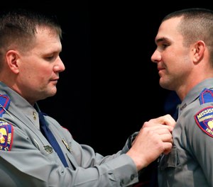 Cadet Jonathan Mark Steed, right, smiles as his father, Mississippi Bureau of Investigation Lt. Mark Steed, left, has difficulty in pinning the Mississippi Highway Patrol badge on him, Wednesday, May 1, 2019, during their graduation ceremony, in Pearl, Miss. (AP Photo/Rogelio V. Solis)
