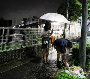 A couple places flowers near the Kyoto Animation building that was destroyed in an arson attack in Kyoto, Japan. (AP Photo/Jae C. Hong)