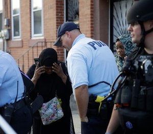 A police officer comforts a bystander near the scene of a shooting on Wednesday, Aug. 14, 2019, in Philadelphia where a gunman opened fire on police as they were serving a warrant, wounding several officers.