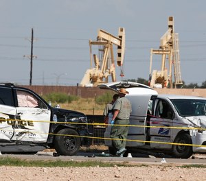 Law enforcement officials process the crime scene Sunday, Sept. 1, 2019, in Odessa, Texas, from Saturday's shooting which ended with the alleged shooter being shot dead by police in a stolen mail van, right.