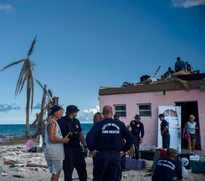 Randy Nagy, center, talks with firefighters arriving from the city of Miami to help those affected by Hurricane Dorian while his wife Silvia, 63, goes out the door of his destroyed house in Pelican Point, Grand Bahama, Bahamas, Monday, Sept. 9, 2019. (AP Photo/Ramon Espinosa)