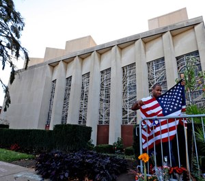 A man places an American flag outside the Tree of Life synagogue in Pittsburgh on Sunday, Oct. 27, 2019, the first anniversary of the shooting at the synagogue that killed 11 worshippers. (AP Photo/Gene J. Puskar)