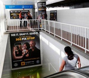 Pedestrians on an escalator pass large posters aimed at curbing sex trafficking, Wednesday, Nov. 6, 2019, at the Metromover Knight Center Station in Miami. Authorities in Miami are launching the initiative in the events surrounding February's Super Bowl.