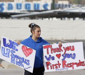 Student Sayla David, 12, holds thank you signs for first responders outside the Saugus High School in Santa Clarita, Calif., Friday, Nov. 15, 2019. (AP Photo/Damian Dovarganes)