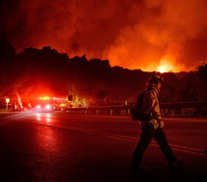 Un pompier traversează autostrada 154 în timp ce luptă împotriva incendiului Cave Fire din Pădurea Națională Los Padres, California, deasupra Santa Barbara, marți, 26 noiembrie 2019.