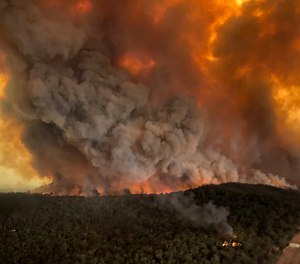 In this Monday, Dec. 30, 2019, aerial photo, wildfires rage under plumes of smoke in Bairnsdale, Australia. Two dozen people have been charged with intentionally lighting fires during the crisis that has claimed 25 lives and destroyed 2,000 homes.