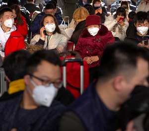 Travelers wear face masks as they sit in a waiting room at the Beijing West Railway Station in Beijing, Tuesday, Jan. 21, 2020. A fourth person has died in an outbreak of a new coronavirus in China, authorities said Tuesday, as more places stepped up medical screening of travelers from the country as it enters its busiest travel period.