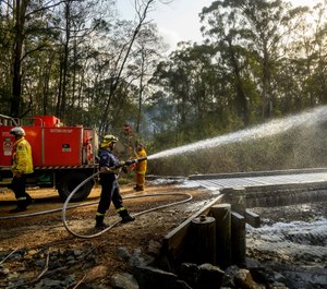 A firefighter coats a bridge with foam as a bushfire burns near Moruya, New South Wales, Australia, Saturday, Jan. 25, 2020. Wildfires destroyed more than 3,000 homes and razed more than 26 million acres since September. (AP Photo/Noah Berger)