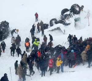 Emergency service members work in the snow around overturned vehicles, near the town of Bahcesaray, Van province, eastern Turkey, Wednesday, Feb. 5, 2020. An avalanche slammed into a mountain road in the province, which borders Iran, wiping out a huge team of rescue workers sent to find two people missing in an earlier avalanche.