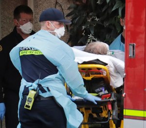 A patient is loaded into an ambulance, Tuesday, March 10, 2020, at the Life Care Center in Kirkland, Wash., near Seattle. The nursing home is at the center of the outbreak of the coronavirus in Washington state. (AP Photo/Ted S. Warren)