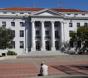 A man sits across from Sproul Hall on the University of California campus in Berkeley, Calif., Wednesday, March 11, 2020.