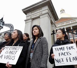 Members of the Mass. Asian American Commission stand together during a protest, Thursday, March 12, 2020, on the steps of the Statehouse in Boston. Asian American leaders in Massachusetts condemned what they say is racism, fear-mongering and misinformation aimed at Asian communities amid the widening coronavirus pandemic that originated in China.
