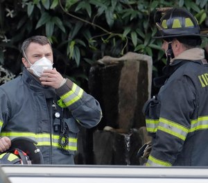 In this March 11, 2020 photo, a Kirkland firefighter wears a mask as he responds to an automatic fire alarm that was accidentally triggered at the Life Care Center in Kirkland, Wash., near Seattle.