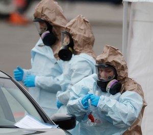 Colorado National Guard medical personnel perform coronavirus test on a motorist at a drive-through testing site outside the Denver Coliseum Saturday, March 14, 2020, in Denver.