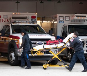 Emergency Medical Technicians wheel a collapsible wheeled stretcher into the emergency room at NewYork-Presbyterian Lower Manhattan Hospital, Wednesday, March 18, 2020, in New York.