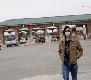 A pedestrian wears a protective mask as he passes the entrance to the McAllen Hidalgo International Bridge, Saturday, March 21, 2020, in Hidalgo, Texas.