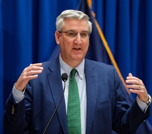 Indiana Gov. Eric Holcomb speaks at a press briefing at the Statehouse in Indianapolis, Tuesday, March 24, 2020. This week, Holcomb issued an executive order allowing retired or inactive EMS providers to work under the supervision of a licensed EMS or healthcare professional. (AP Photo/Michael Conroy)