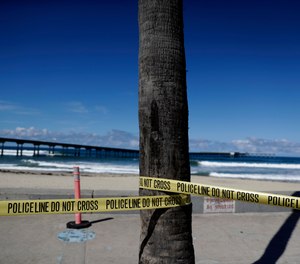 Police tape closes access to a beach Tuesday, March 24, 2020, in San Diego. San Diego tightened restrictions on beach access Monday, as the city reacts to the coronavirus pandemic.