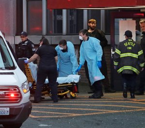 Police, fire, and EMS responders, some wearing masks, gowns, and gloves to protect against the transmission of the new coronavirus, respond to a medical call in Seattle Tuesday, March 24, 2020.