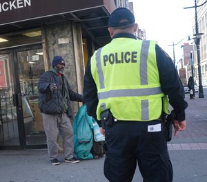 A police officer asks a man to keep moving in an effort to encourage social distancing at an intersection in Newark, N.J., Thursday, March 26, 2020. Police departments are taking a lead role in enforcing social distancing guidelines that health officials say are critical to containing COVID-19.