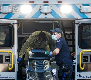 Crewmembers load oxygen and disinfect surfaces of an ambulance outside a COVID-19 testing side at Elmhurst Hospital Center, Friday, March 27, 2020, in New York. A Change.org petition has been launched calling for hazard pay for first responders and healthcare personnel during the COVID-19 national health emergency.