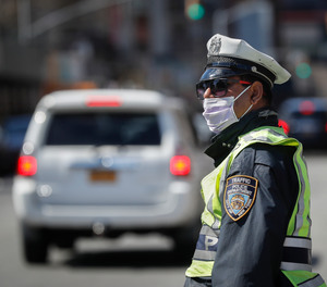 An NYPD traffic officer wearing personal protective equipment stands at a barricade after the city closed down a section of Bushwick Avenue due to COVID-19 concerns, Friday, March 27, 2020, in the Brooklyn borough of New York.