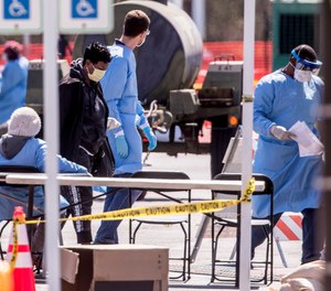 Medical personnel wearing protective equipment screen people referred by doctors for COVID-19 testing in a parking lot of FedEx Field, Monday, March 30, 2020, in Landover, Md.