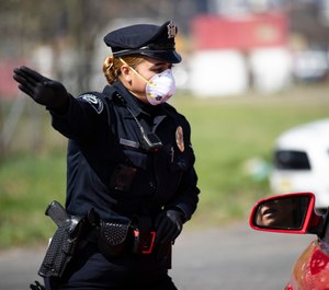 Camden County Police Officer Rodriguez wears a protective mask as she directs people to a COVID-19 testing facility in Camden, N.J., Wednesday, April 1, 2020. (AP Photo/Matt Rourke)