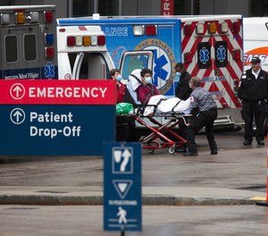 An ambulance crew transports a patient at the Massachusetts General Hospital emergency entrance, Friday, April 3, 2020, in Boston. Massachusetts lawmakers are considering a proposal that would protect EMS providers, healthcare workers and health facilities from legal liability while making difficult decisions during the COVID-19 crisis.