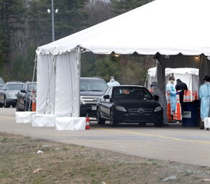 Drivers line up for a coronavirus test at a site in a parking lot at Gillette Stadium, Sunday, April 5, 2020, in Foxborough, Mass. The site, which opened Sunday, is designated specifically for first responders who may have been exposed or are showing virus symptoms.
