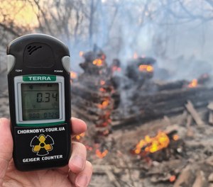 A Geiger counter shows increased radiation level against the background of the forest fire burning near the village of Volodymyrivka in the exclusion zone around the Chernobyl nuclear power plant, Ukraine, Sunday, April 5, 2020.