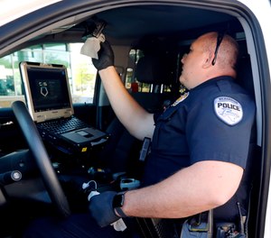 Richardson police officer Dustin Penland uses gloves as he wipes down the interior of his vehicle with disinfectant wipes at the start of his shift change, Wednesday, April 8, 2020.